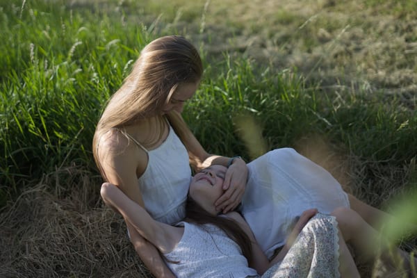Two people outdoors in a relaxed family portrait, wide landscape framing