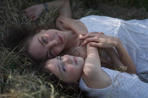Two people together in a sunlit outdoor setting, landscape orientation