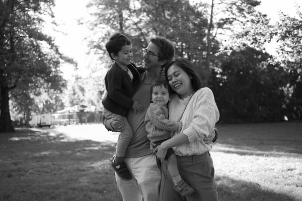 Family of four laughing together in a park, black and white