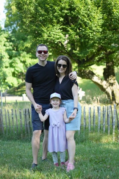 Family portrait in front of a garden fence, toddler standing between parents