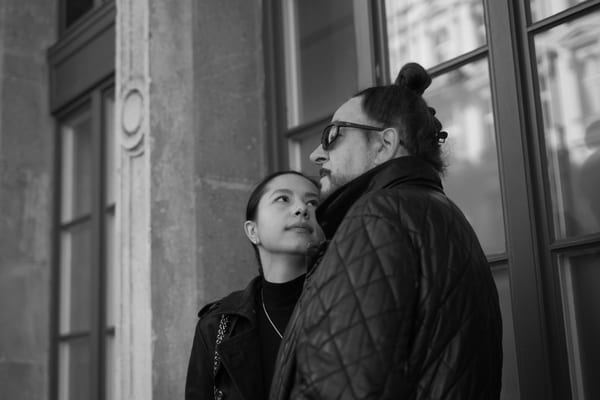 Woman looking up at her partner in sunglasses beside a tall window