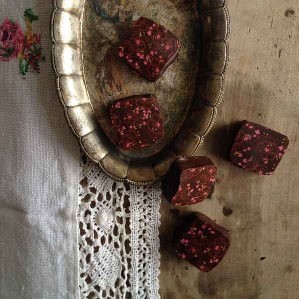 Chocolate petit fours in a vintage brass tray on embroidered linen with crocheted lace trim