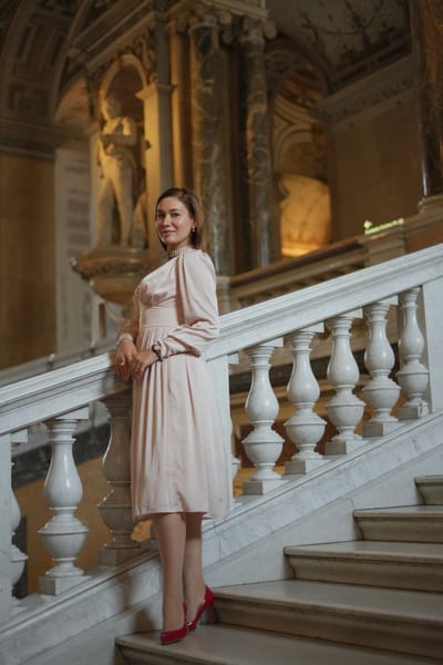 Full-length portrait in a pink dress and red heels on the marble steps of the Kunsthistorisches Museum
