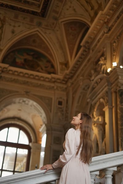 Woman looking up at painted ceiling frescoes from a balcony inside a Vienna palace