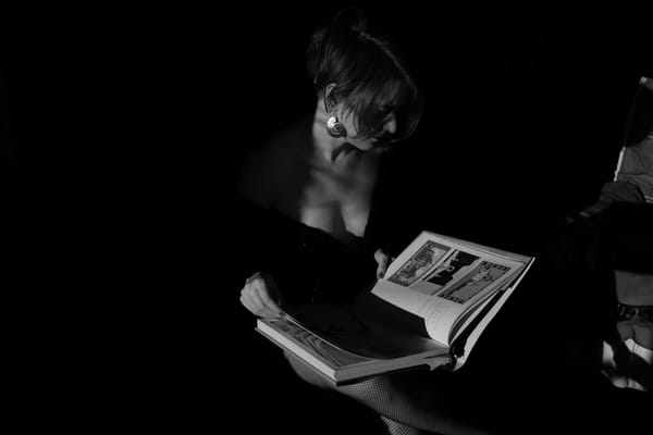 Woman reading a photo book in dramatic black and white light, dark background