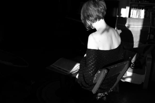 Black and white portrait from behind, bare shoulders and short hair lit by a window
