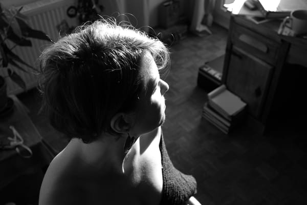 Close-up profile portrait in black and white, sunlight catching short curly hair