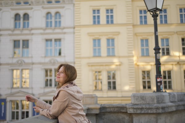 Woman leaning on a stone parapet in warm afternoon sun, Ringstrasse buildings and a street lamp behind her
