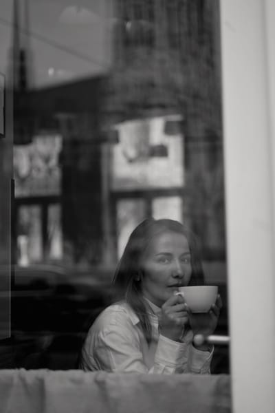 Woman sipping coffee in a Vienna café, shot through the window in black and white