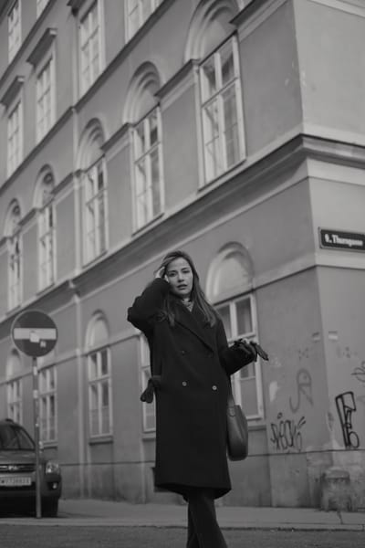 Woman in a dark coat walking past a street sign on Thurngasse in Vienna