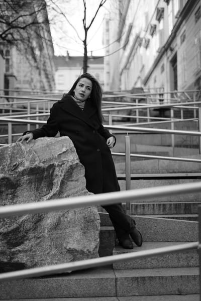 Portrait leaning on a stone block by metal railings, urban Vienna backdrop
